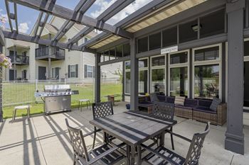 A patio with a table and chairs is covered by a roof.